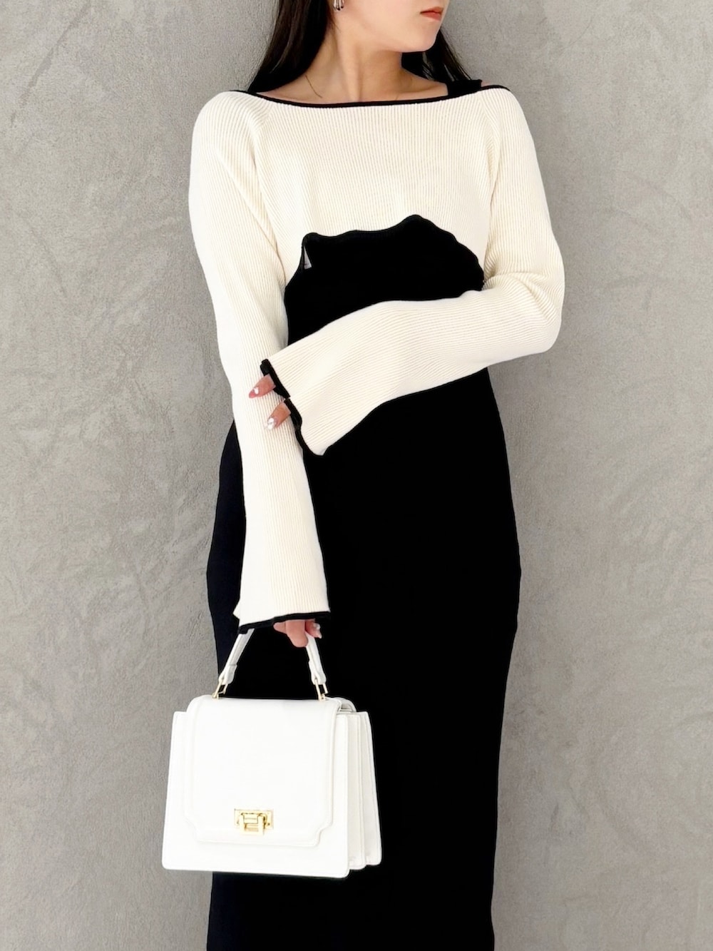 ブラック系のブーツ、ホワイト系のハンドバッグ、ブラック系のワンピースを着用したレディースの冬コーディネートの7枚目の写真