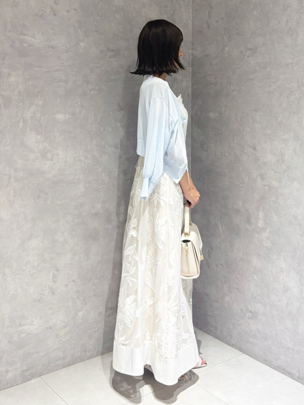 ホワイト系のワンピース、ホワイト系のサンダル、ホワイト系のハンドバッグを着用したレディースの夏コーディネートの4枚目の写真