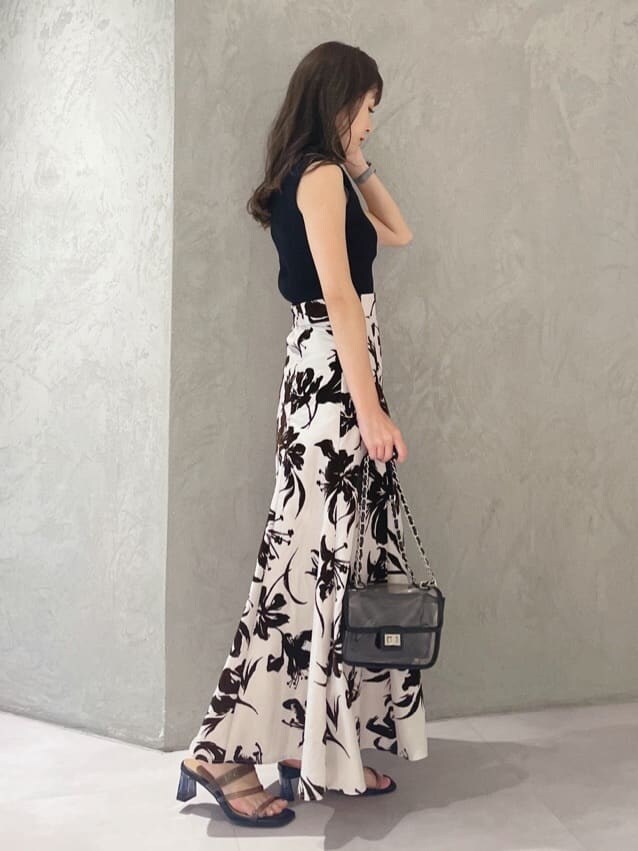 ブラック系のニット/セーター、ホワイト系のスカート、ブラック系のショルダーバッグを着用したレディースの夏コーディネートの4枚目の写真