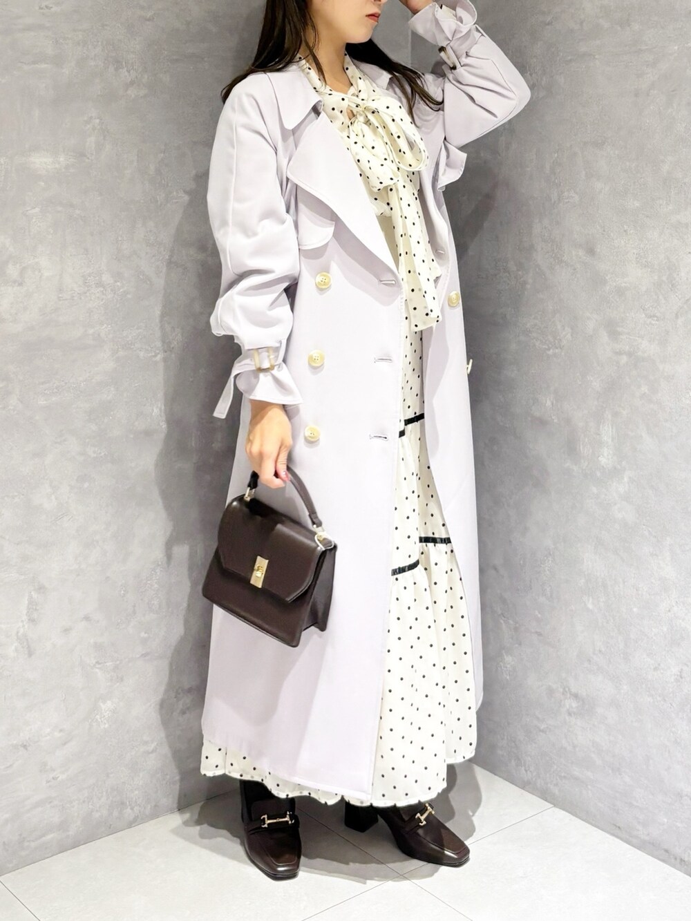 ホワイト系のワンピース、パープル系のトレンチコート、ブラウン系のハンドバッグを着用したレディースの冬コーディネートの5枚目の写真