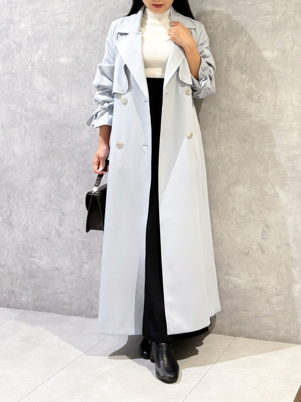 ブラック系のスカート、ブラック系のブーツ、ブラウン系のハンドバッグを着用したレディースの冬コーディネートの5枚目の写真