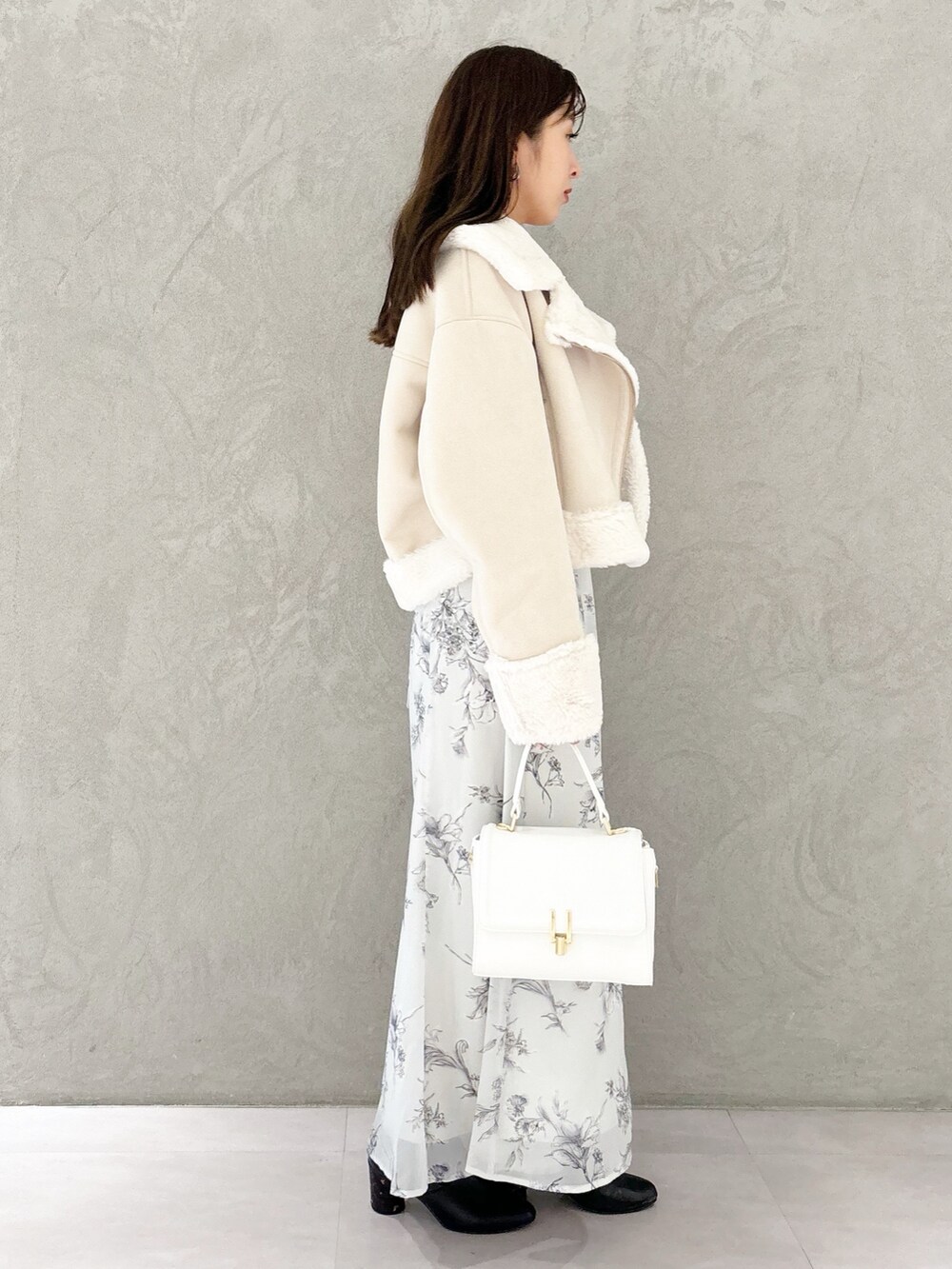 ブラック系のワンピース、ブラック系のブーツ、ホワイト系のハンドバッグを着用したレディースの秋コーディネートの8枚目の写真