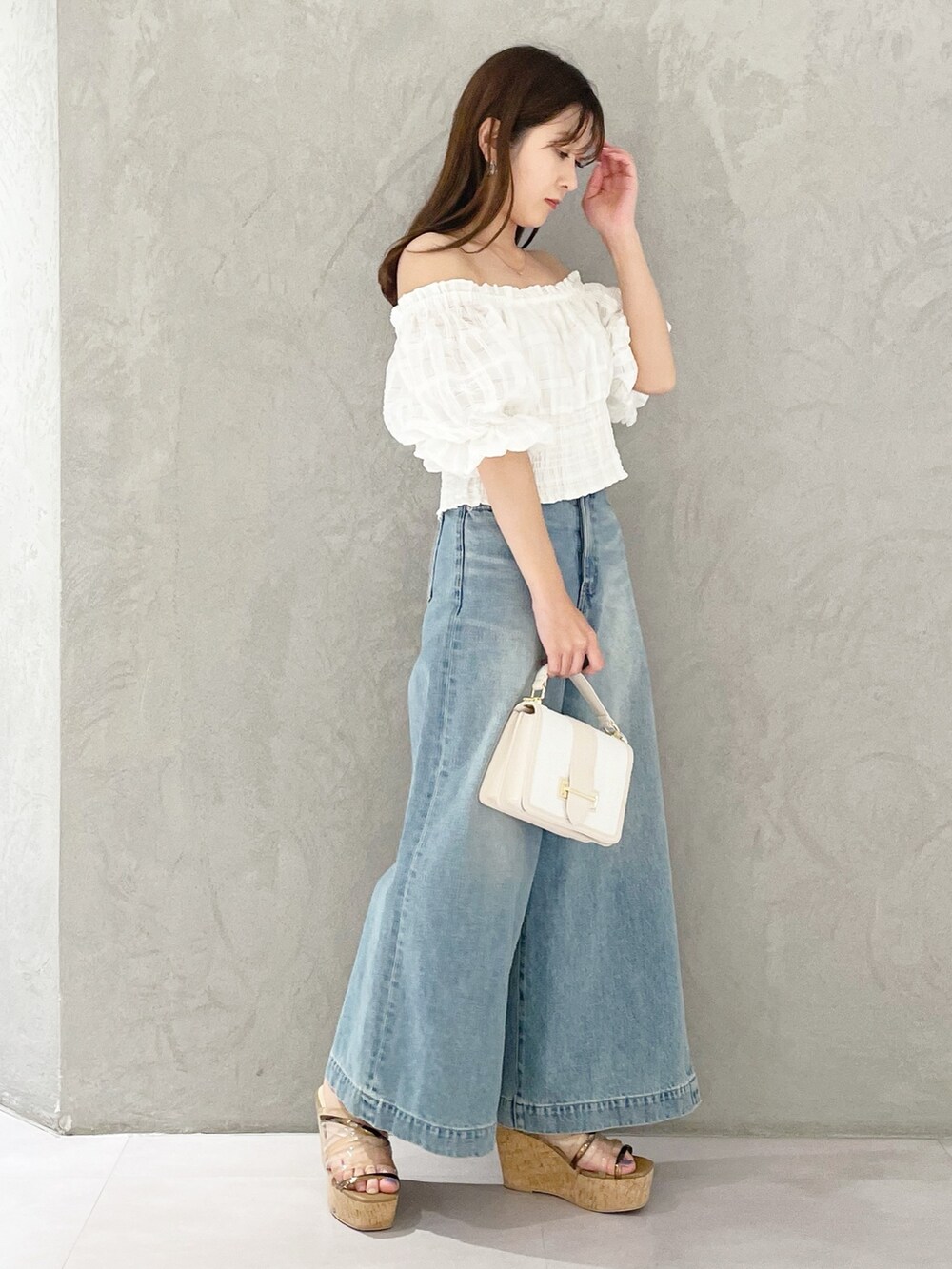 ブルー系のデニムパンツ、ブラウン系のサンダル、ホワイト系のハンドバッグを着用したレディースの春コーディネートの5枚目の写真