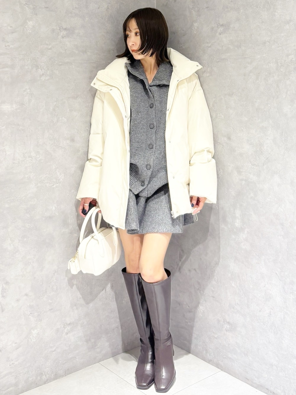 グレー系のワンピース、ホワイト系のダウンジャケット/コート、ホワイト系のハンドバッグを着用したレディースの冬コーディネートの5枚目の写真
