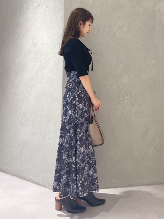 ブラック系のニット/セーター、ブラウン系のハンドバッグ、ブルー系のスカートを着用したレディースの夏コーディネートの2枚目の写真