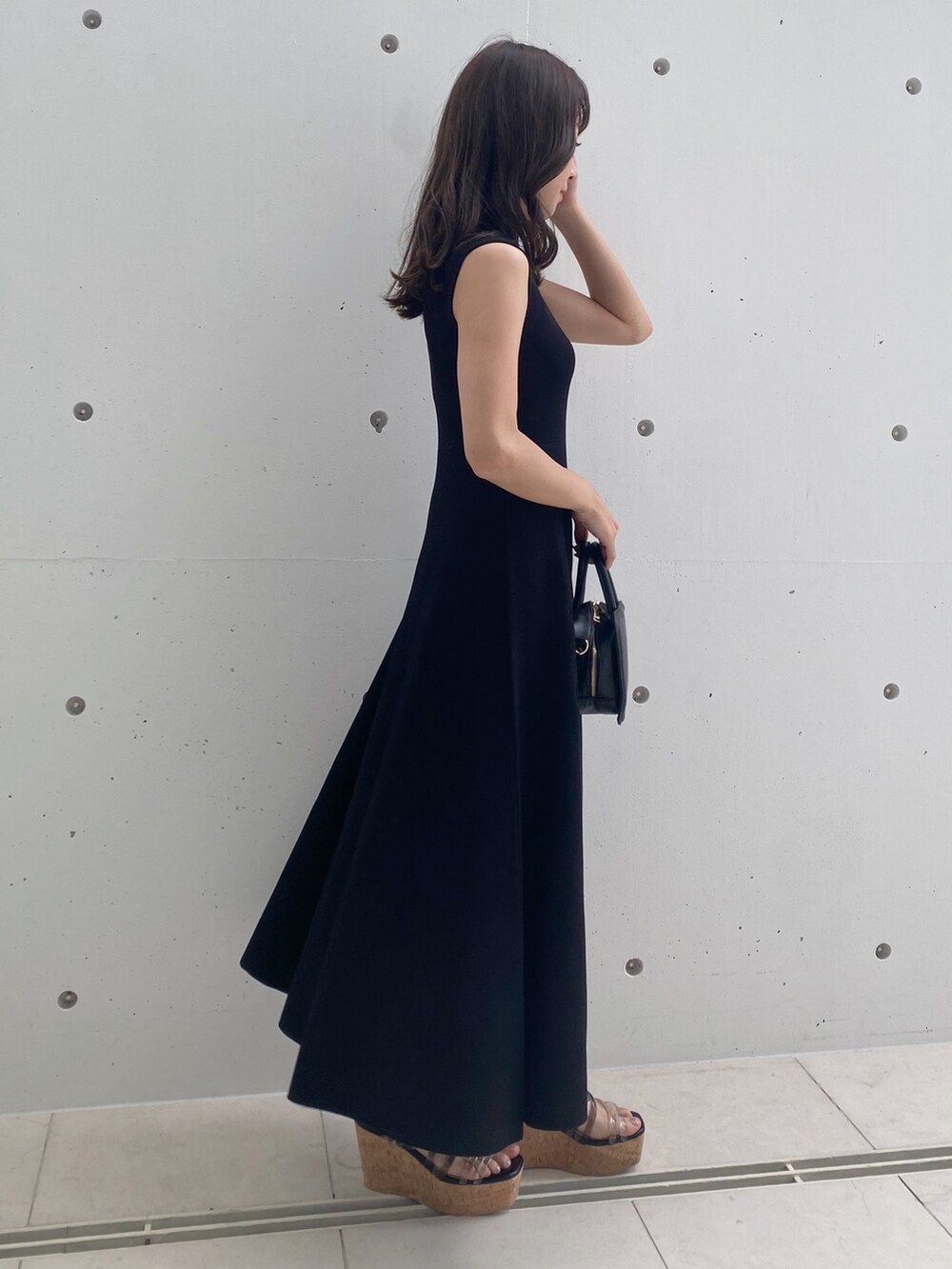 ブラック系のワンピース、ブラック系のサンダル、ブラック系のハンドバッグを着用したレディースの春コーディネートの5枚目の写真