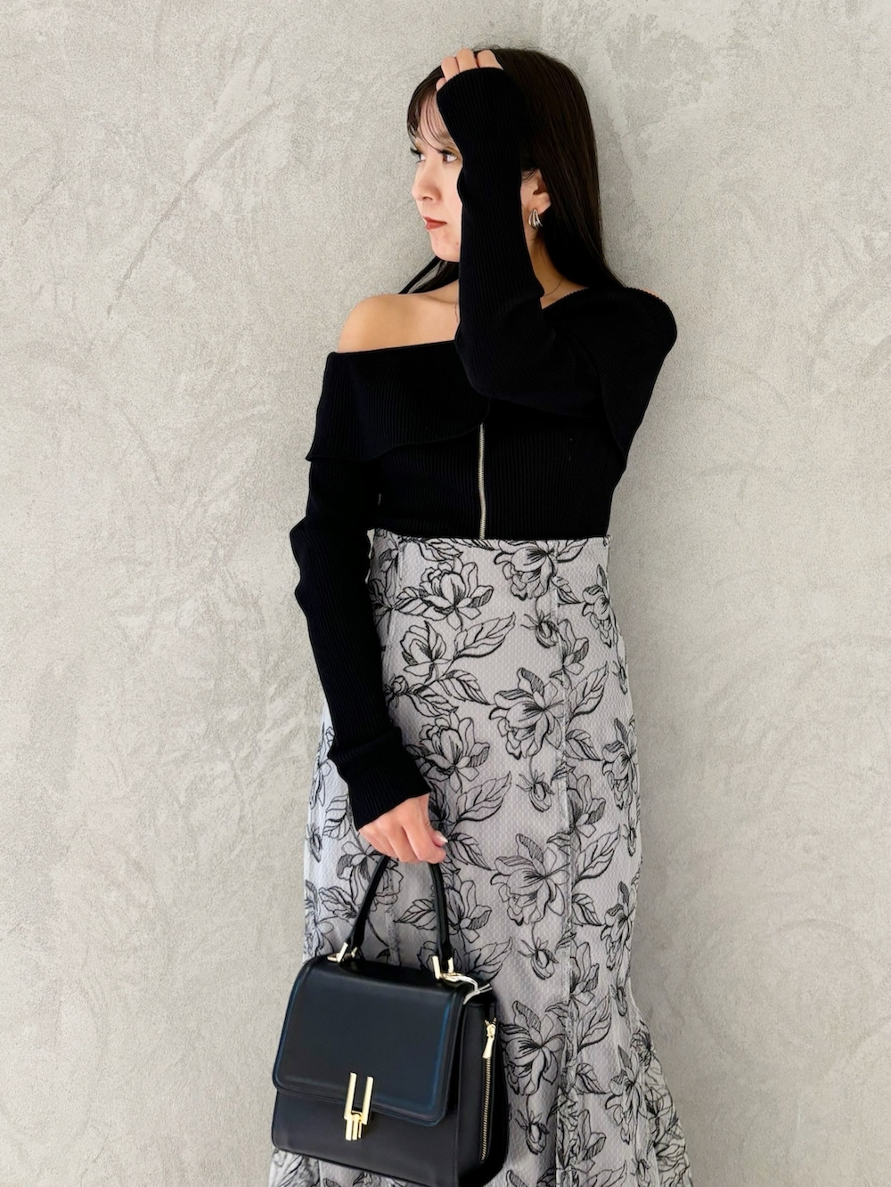 グレー系のスカート、ブラック系のブーツ、ブラック系のショルダーバッグを着用したレディースの秋コーディネートの2枚目の写真