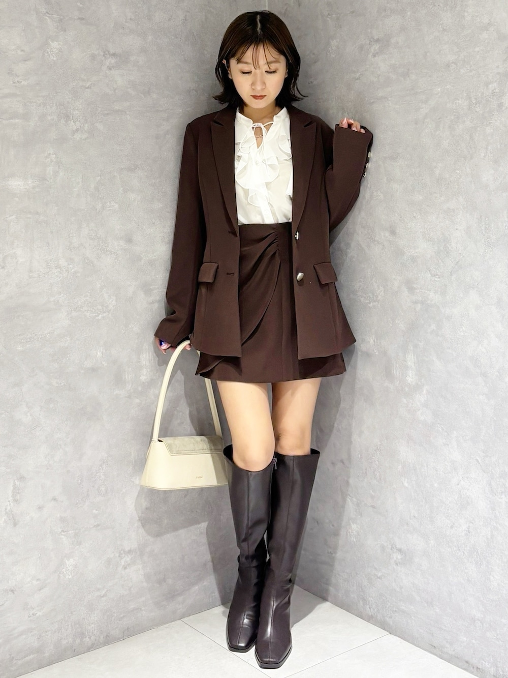 ホワイト系のシャツ/ブラウス、ホワイト系のハンドバッグ、ブラウン系のブーツを着用したレディースの春コーディネートの5枚目の写真