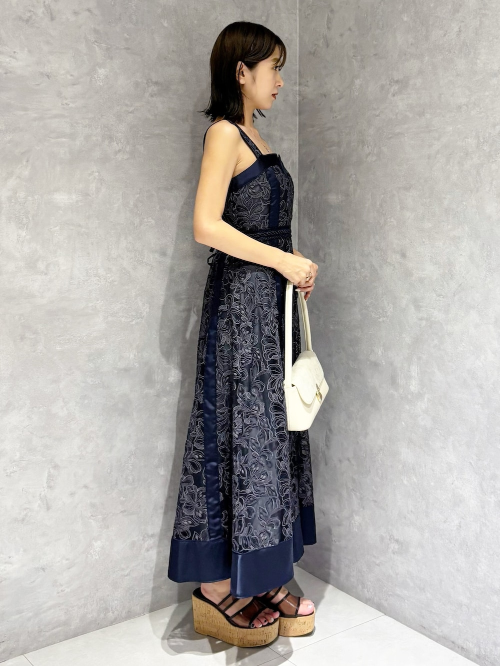 ブルー系のワンピース、ブラウン系のサンダル、ホワイト系のハンドバッグを着用したレディースの夏コーディネートの5枚目の写真