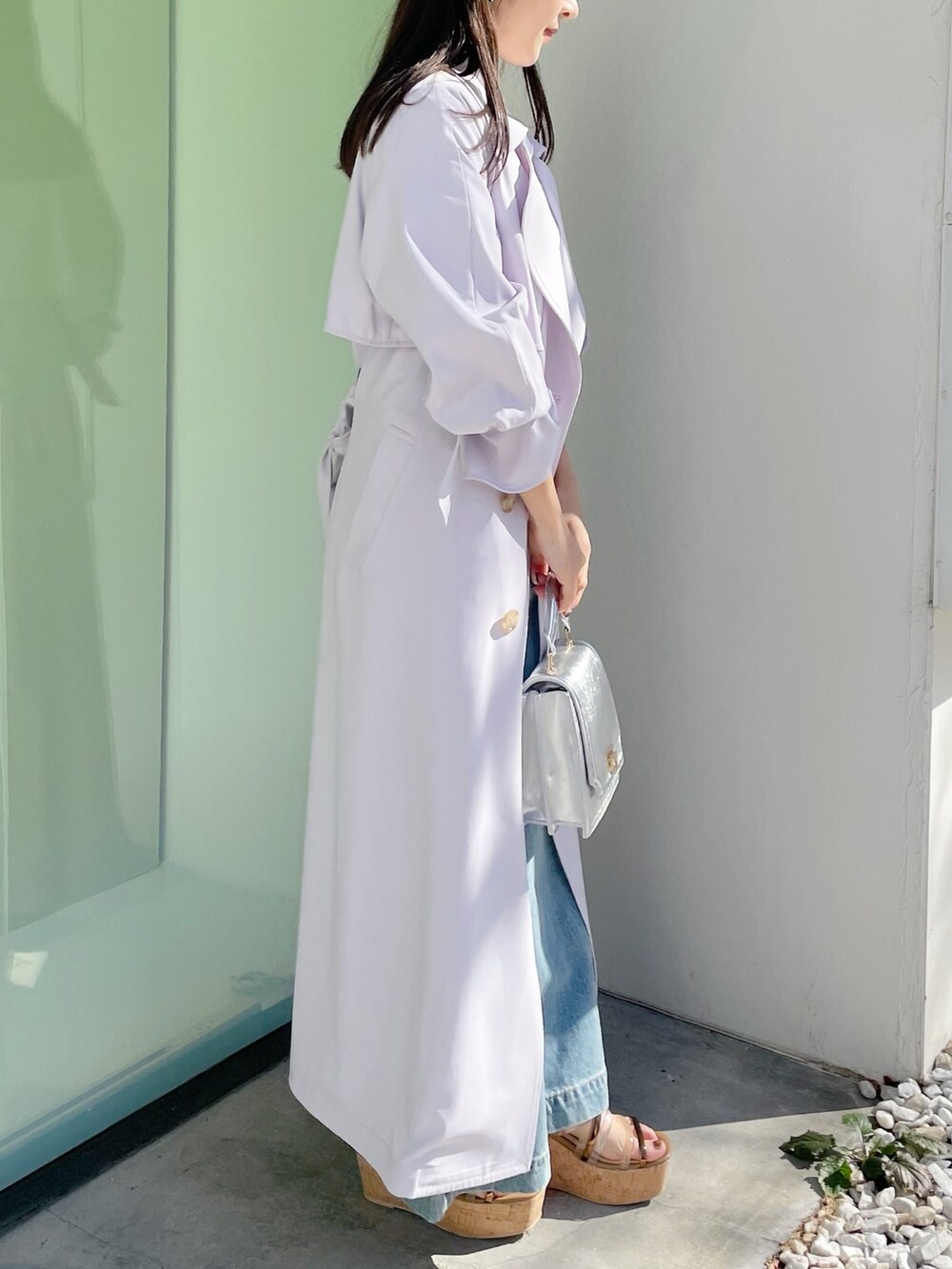 シルバー系のハンドバッグ、ブラック系のサンダル、ブルー系のデニムパンツを着用したレディースの春コーディネートの2枚目の写真