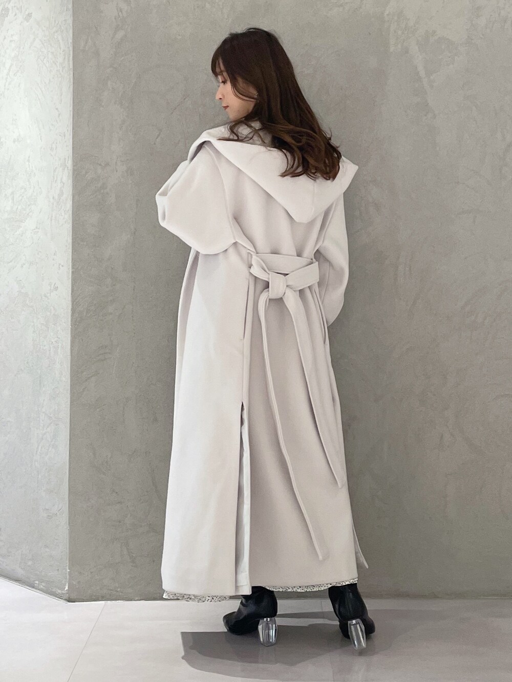 ホワイト系のワンピース、ホワイト系のチェスターコート、ブラック系のブーツを着用したレディースの冬コーディネートの3枚目の写真