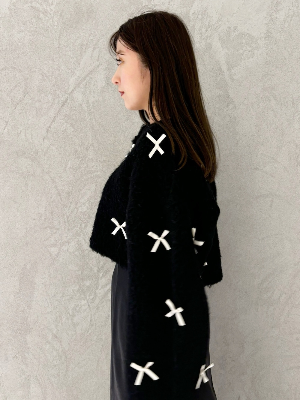 ブラック系のスカート、ブラック系のブーツ、ホワイト系のハンドバッグを着用したレディースの冬コーディネートの3枚目の写真