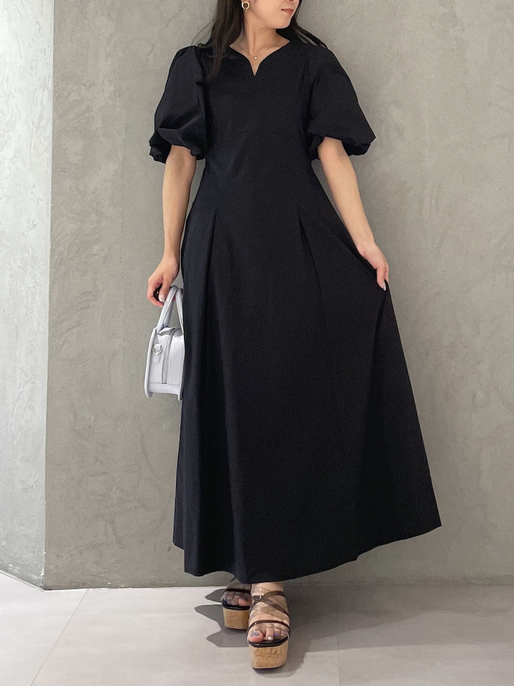 ブラック系のサンダル、ブルー系のハンドバッグ、ブラック系のワンピースを着用したレディースの春コーディネートの4枚目の写真