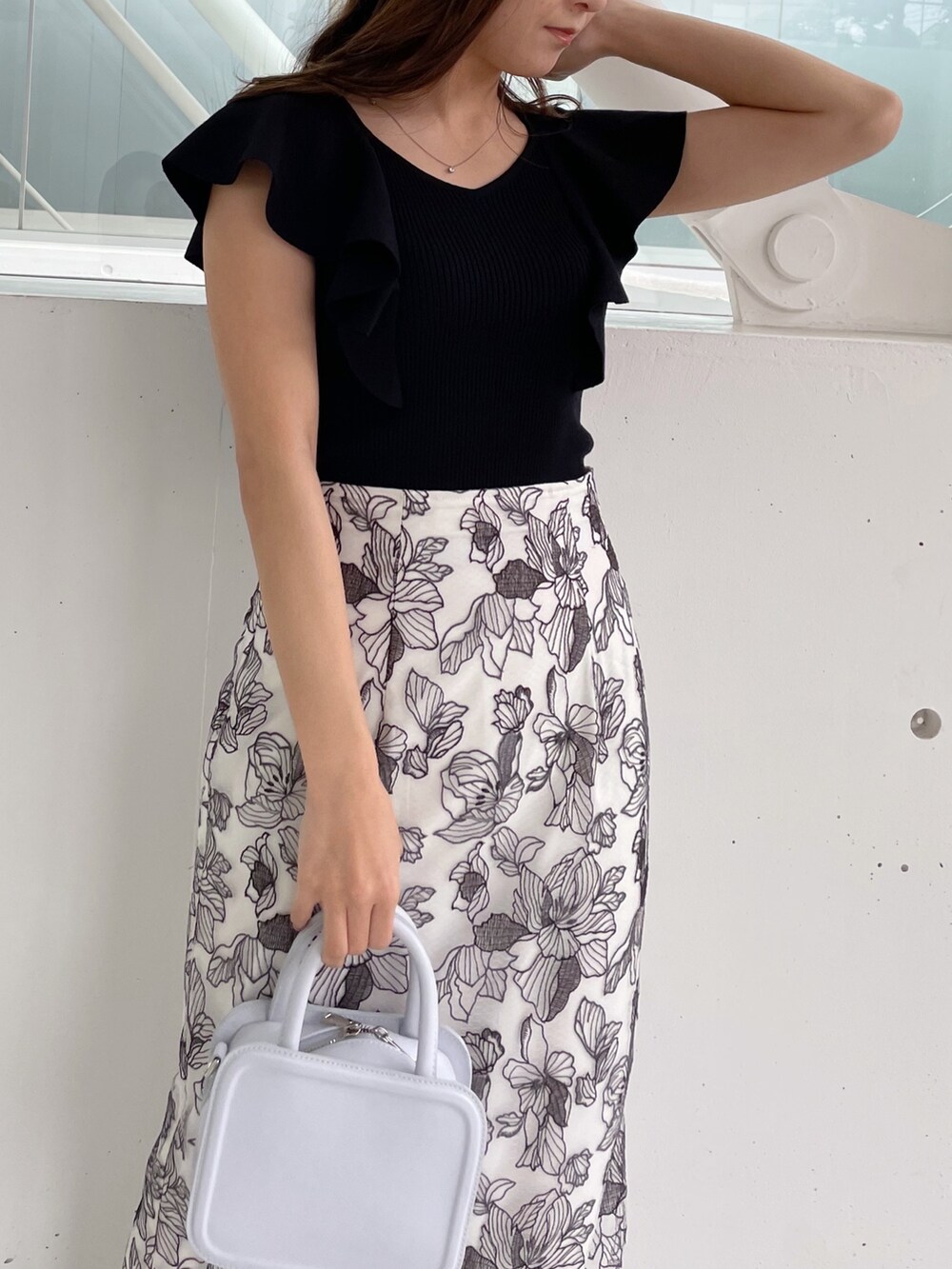 ホワイト系のスカート、ブラック系のニット/セーター、ブラック系のサンダルを着用したレディースの冬コーディネートの3枚目の写真