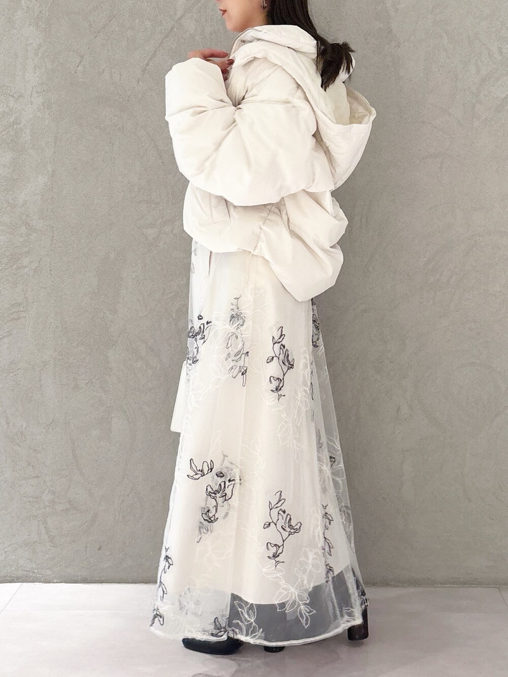 ホワイト系のスカート、ブラック系のブーツ、ホワイト系のハンドバッグを着用したレディースの冬コーディネートの5枚目の写真