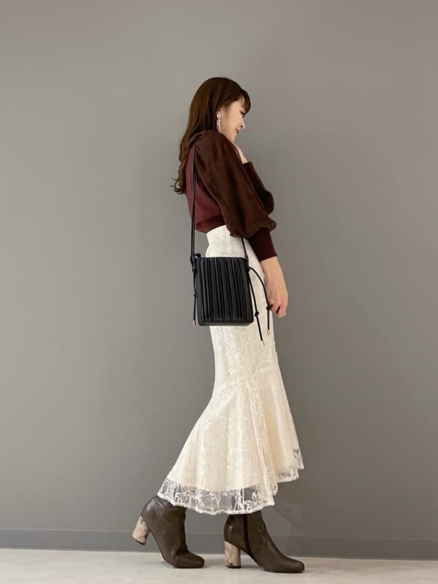 ベージュ系のショルダーバッグ、ブラウン系のカーディガン/ボレロ、ホワイト系のスカートを着用したレディースの冬コーディネートの3枚目の写真