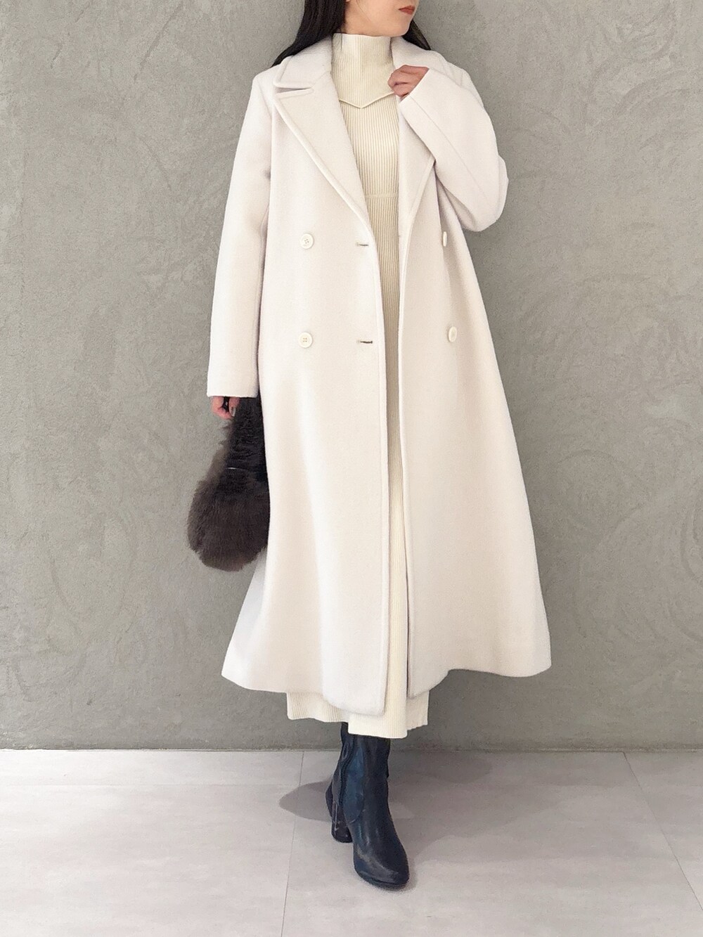 ホワイト系のチェスターコート、ブラック系のブーツ、ブラウン系のハンドバッグを着用したレディースの冬コーディネートの7枚目の写真