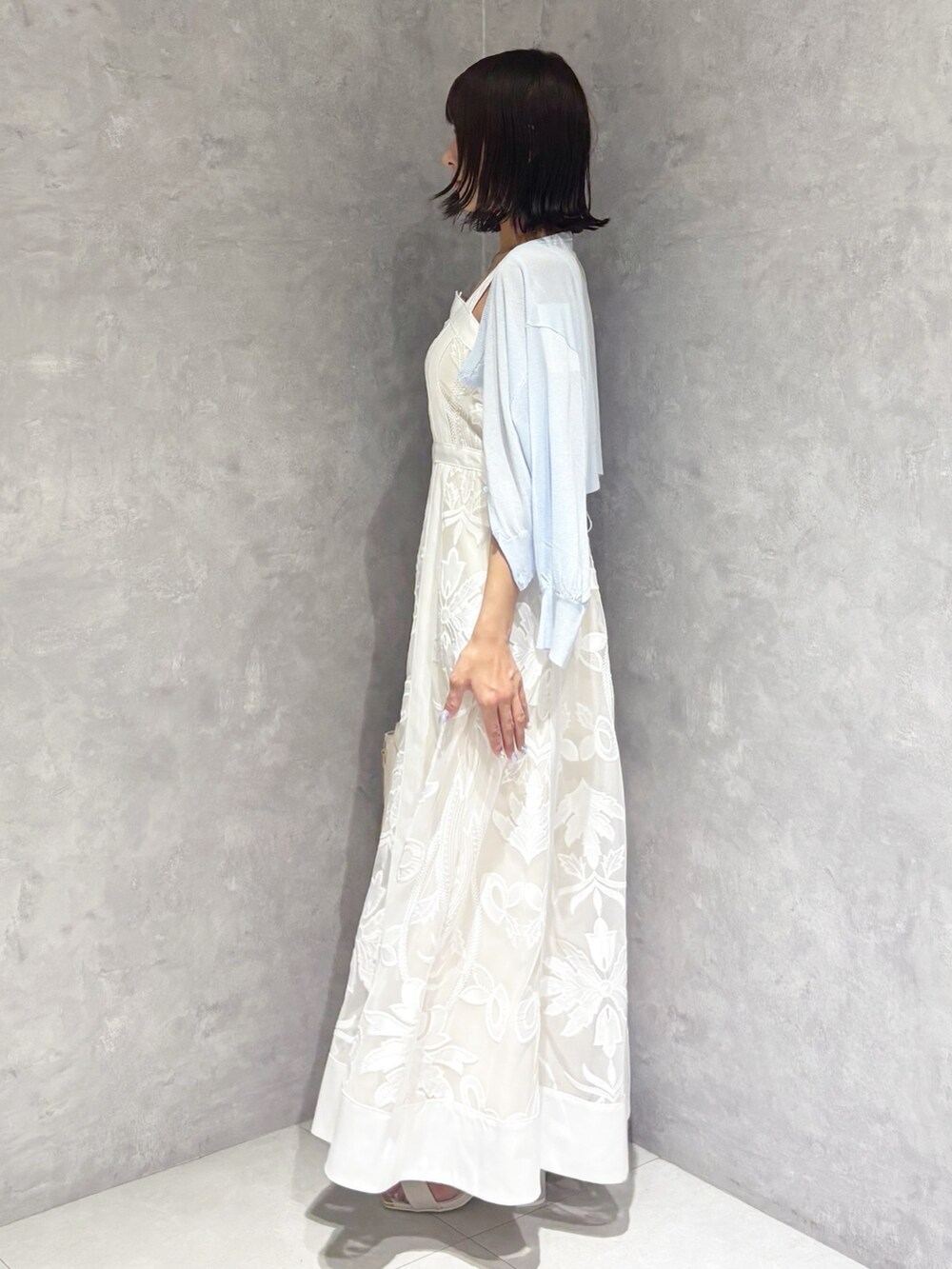 ホワイト系のワンピース、ホワイト系のサンダル、ホワイト系のハンドバッグを着用したレディースの夏コーディネートの2枚目の写真