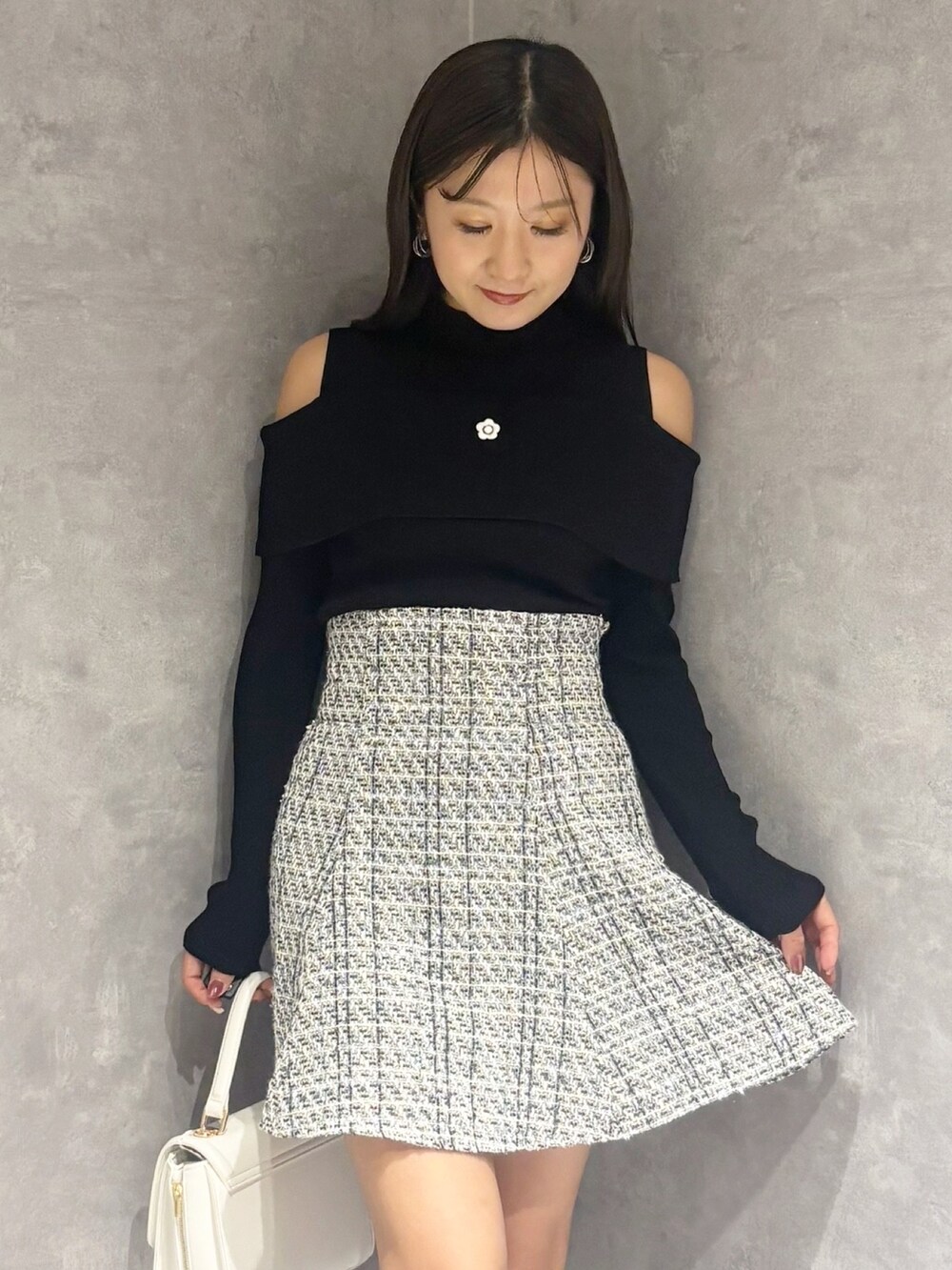 ブラック系のブーツ、ホワイト系のハンドバッグ、ブラック系のニット/セーターを着用したレディースの冬コーディネートの4枚目の写真