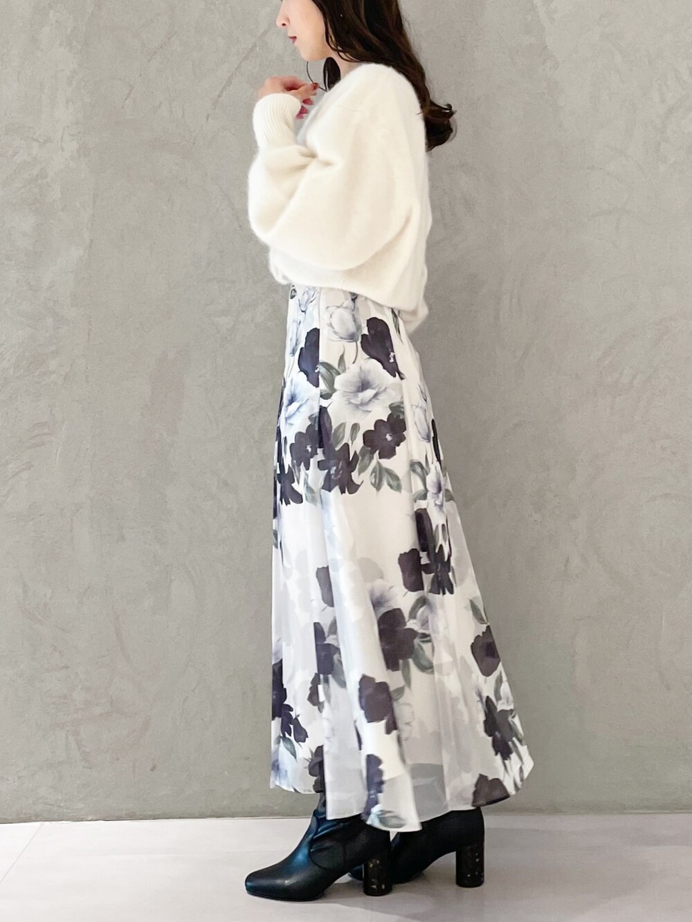 ホワイト系のハンドバッグ、ブラック系のブーツ、ブルー系のスカートを着用したレディースの秋コーディネートの2枚目の写真