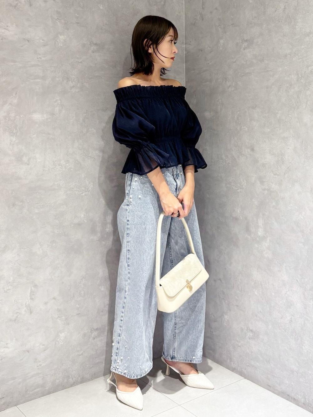 ブルー系のデニムパンツ、ブルー系のシャツ/ブラウス、ホワイト系のハンドバッグを着用したレディースの春コーディネートの2枚目の写真