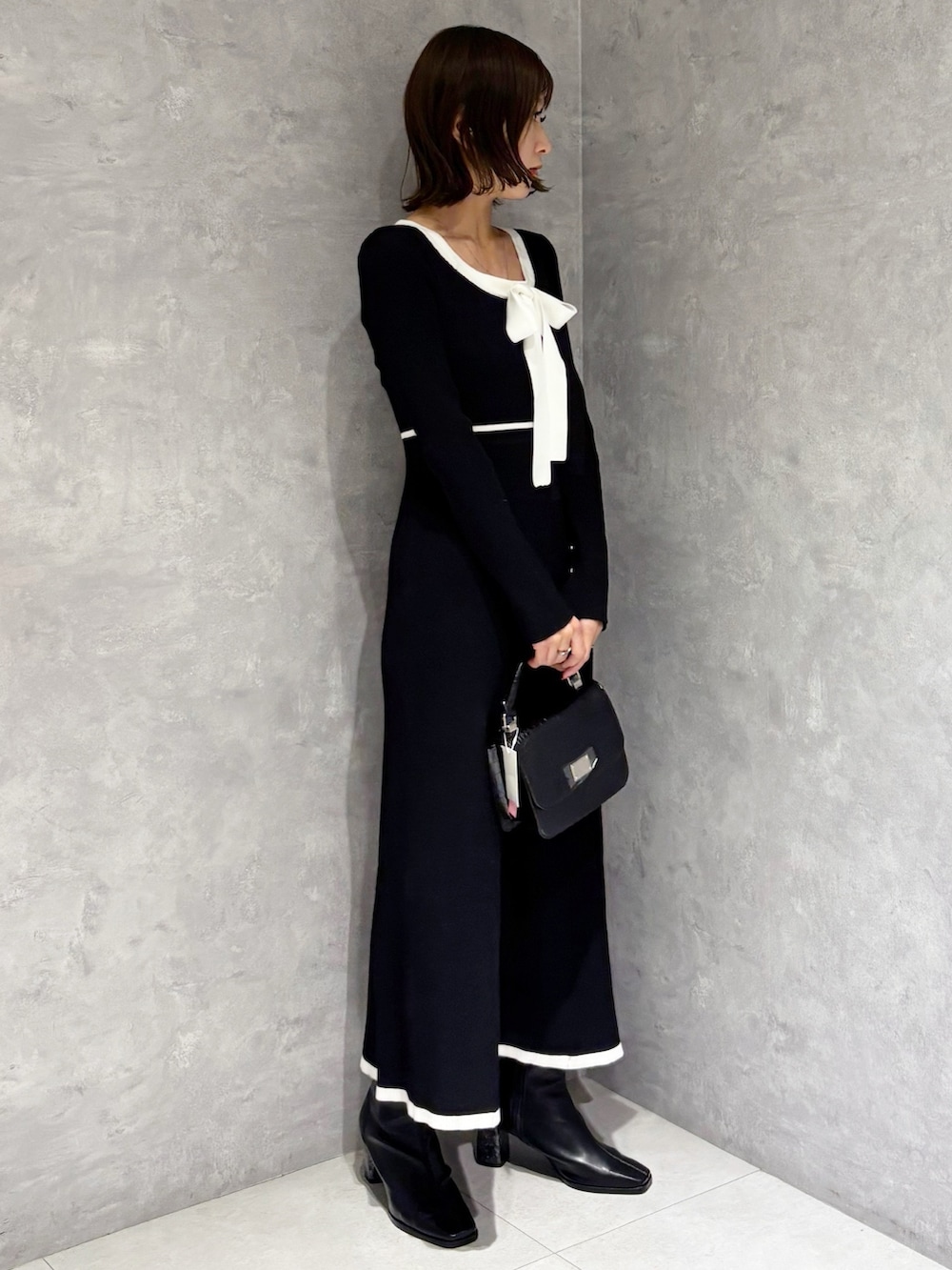 ブラック系のワンピース、ブラック系のハンドバッグ、ブラック系のブーツを着用したレディースの冬コーディネートの5枚目の写真