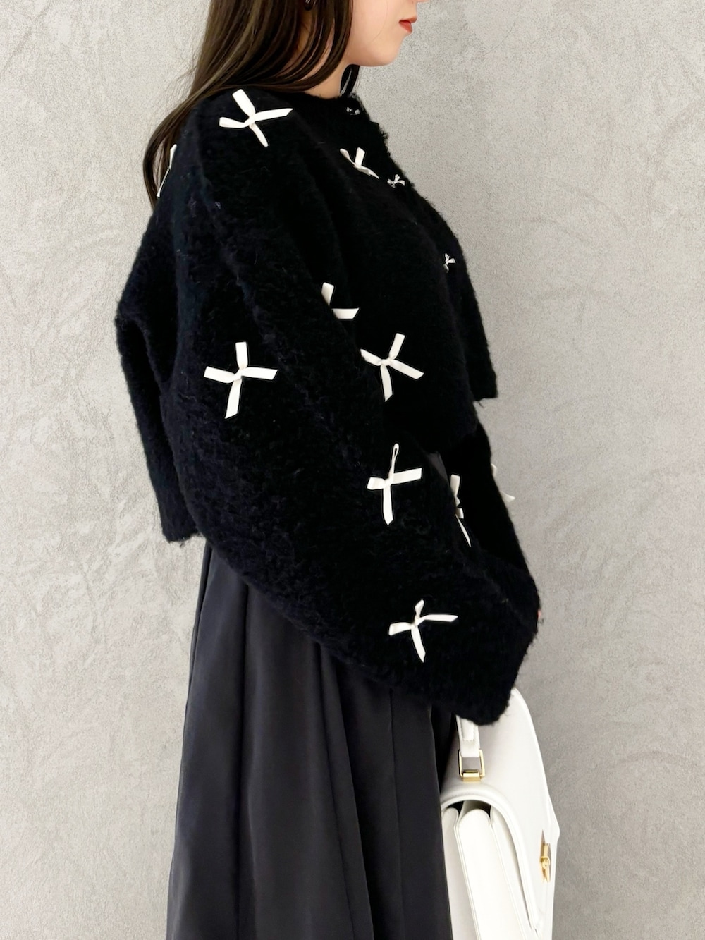 ブラック系のスカート、ブラック系のブーツ、ホワイト系のハンドバッグを着用したレディースの冬コーディネートの2枚目の写真