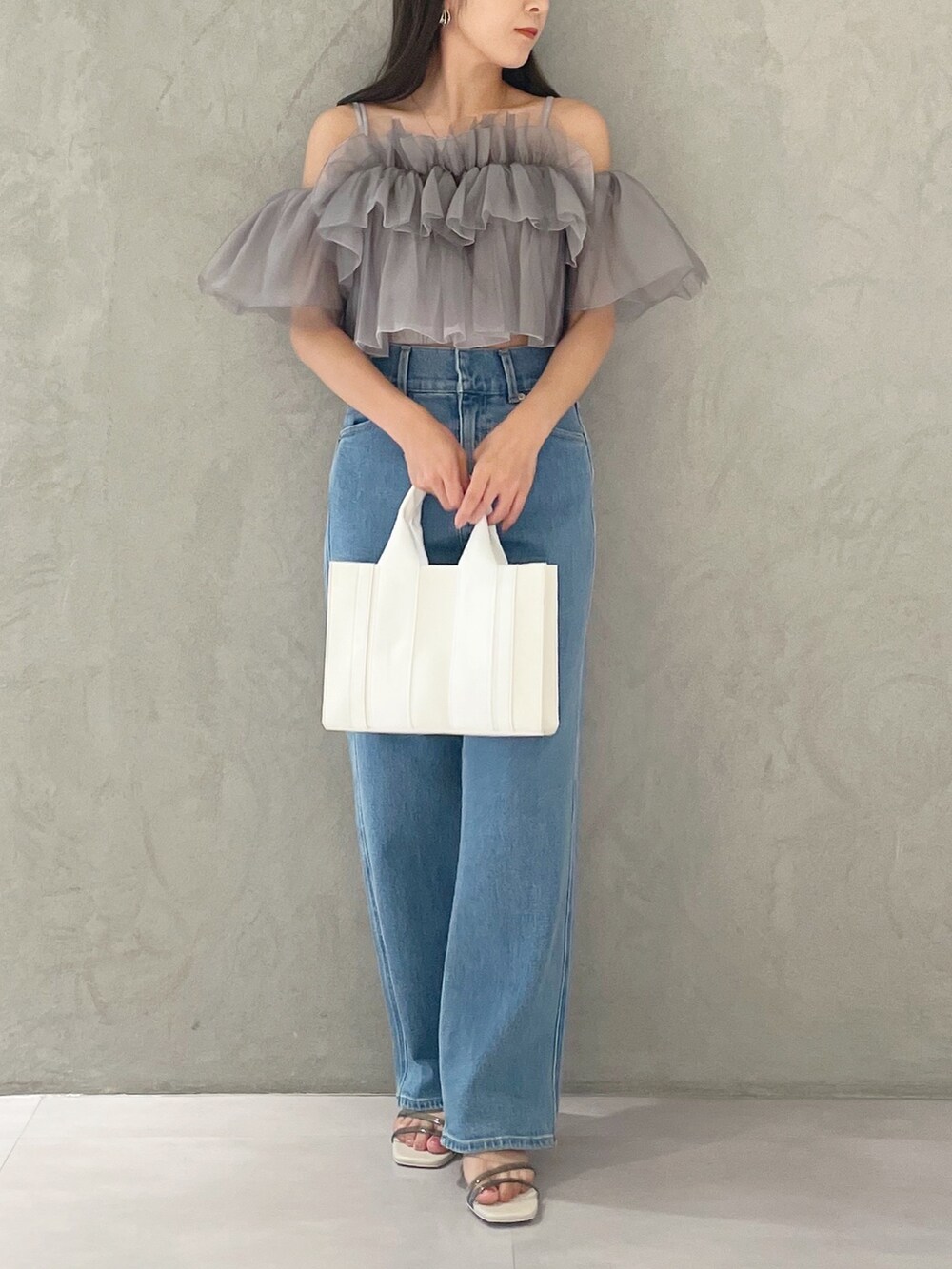 ブルー系のデニムパンツ、ホワイト系のサンダル、ホワイト系のトートバッグを着用したレディースの夏コーディネートの5枚目の写真