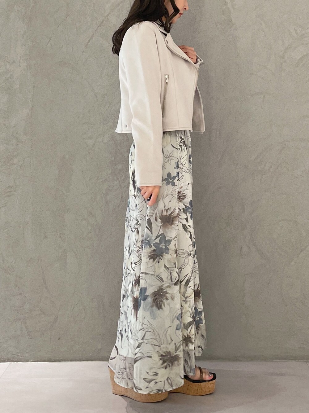 グリーン系のスカート、ピンク系のライダースジャケット、ブラック系のサンダルを着用したレディースの春コーディネートの2枚目の写真