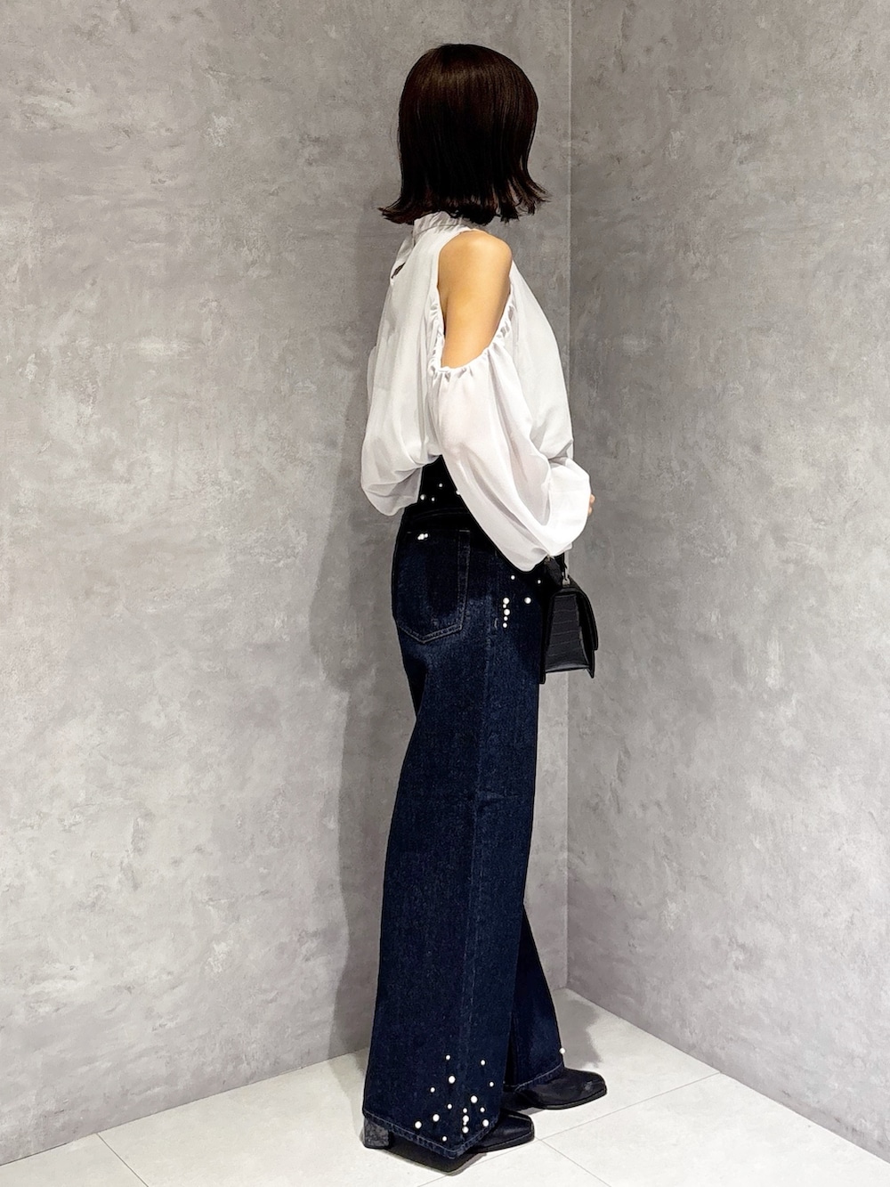 ブルー系のデニムパンツ、ブラック系のブーツ、ブラック系のハンドバッグを着用したレディースの秋コーディネートの3枚目の写真