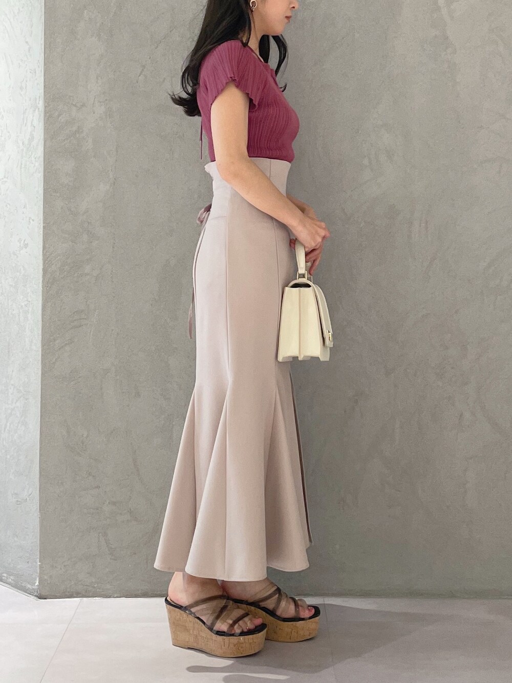 ブラック系のサンダル、ホワイト系のハンドバッグ、ピンク系のスカートを着用したレディースの春コーディネートの2枚目の写真