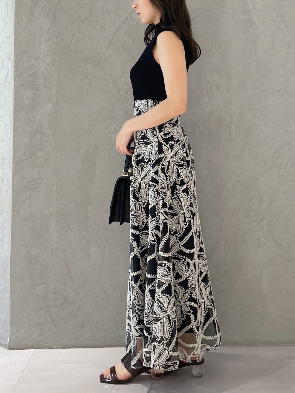 ブラウン系のサンダル、ブラック系のハンドバッグ、ブラック系のニット/セーターを着用したレディースの夏コーディネートの2枚目の写真