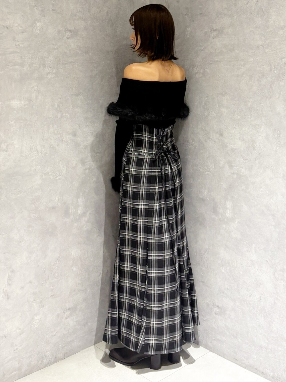 ブラック系のハンドバッグ、ブラック系のニット/セーター、ブラック系のスカートを着用したレディースの秋コーディネートの2枚目の写真