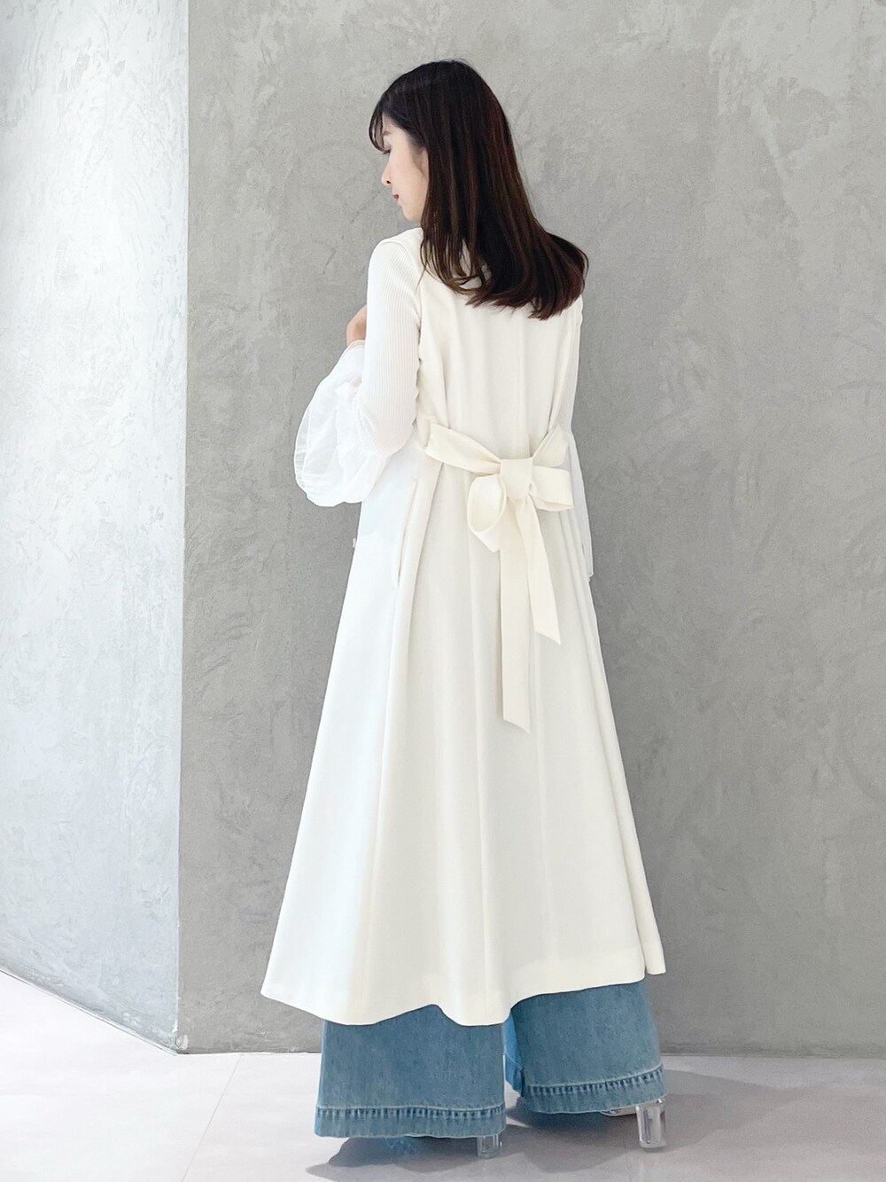 ブルー系のデニムパンツ、ホワイト系のショルダーバッグ、ホワイト系のニット/セーターを着用したレディースの冬コーディネートの4枚目の写真