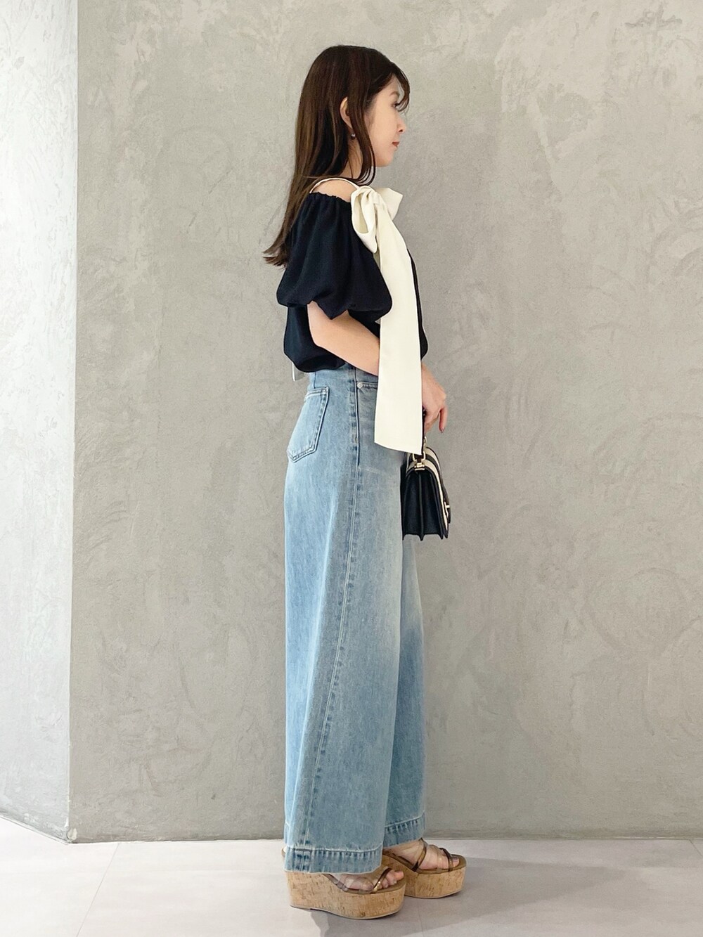 ブラウン系のサンダル、ブラック系のハンドバッグ、ブルー系のデニムパンツを着用したレディースの春コーディネートの3枚目の写真