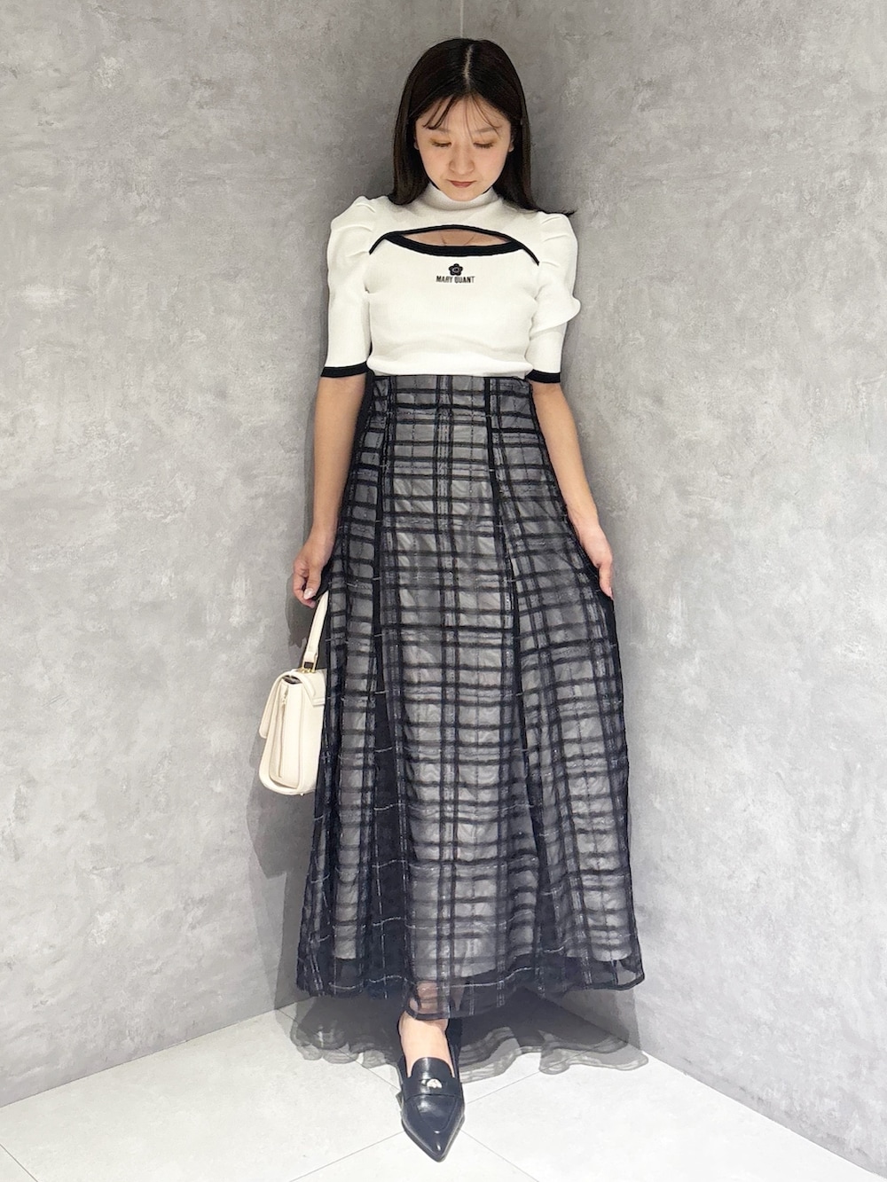 ブルー系のスカート、ブラック系のパンプス、ホワイト系のハンドバッグを着用したレディースの春コーディネートの7枚目の写真