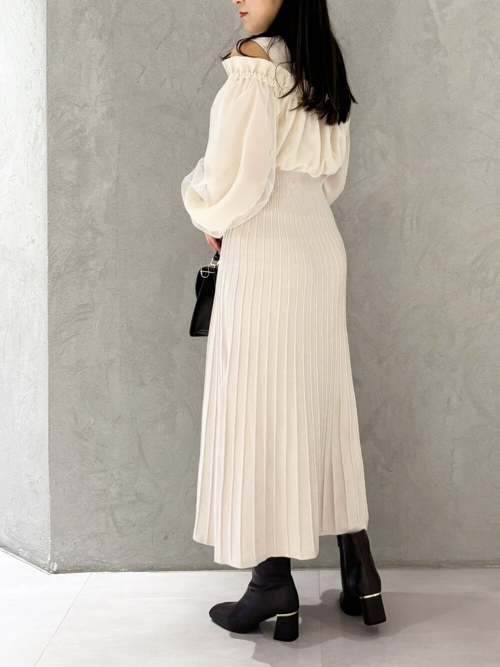 ホワイト系のワンピース、ブラウン系のブーツ、ブラウン系のハンドバッグを着用したレディースの冬コーディネートの5枚目の写真