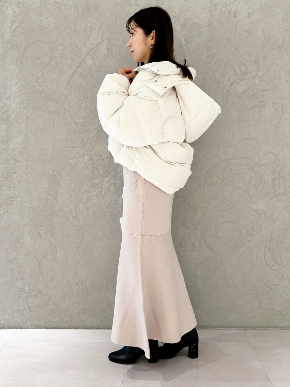 ピンク系のワンピース、ブラック系のブーツ、ホワイト系のショルダーバッグを着用したレディースの秋コーディネートの5枚目の写真