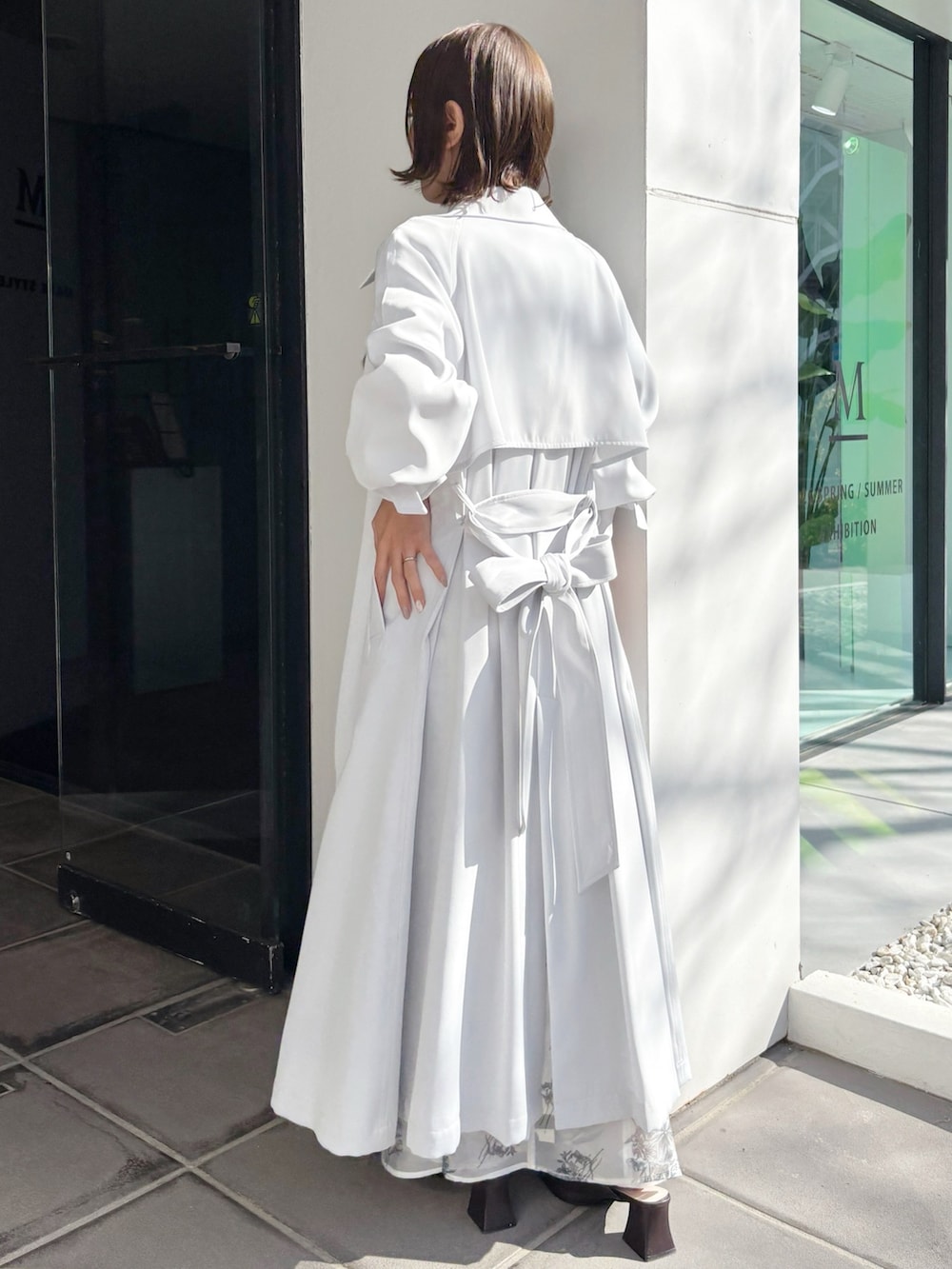 ブラック系のワンピース、ブラウン系のパンプス、ブルー系のトレンチコートを着用したレディースの春コーディネートの6枚目の写真