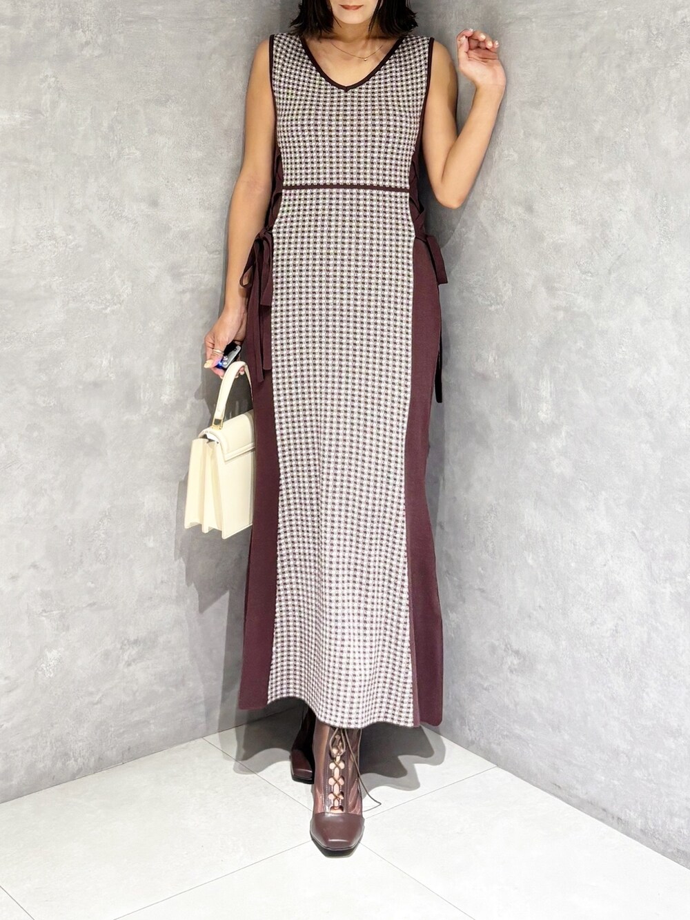 ブラウン系のワンピース、ブラウン系のブーツ、ホワイト系のハンドバッグを着用したレディースの夏コーディネートの7枚目の写真