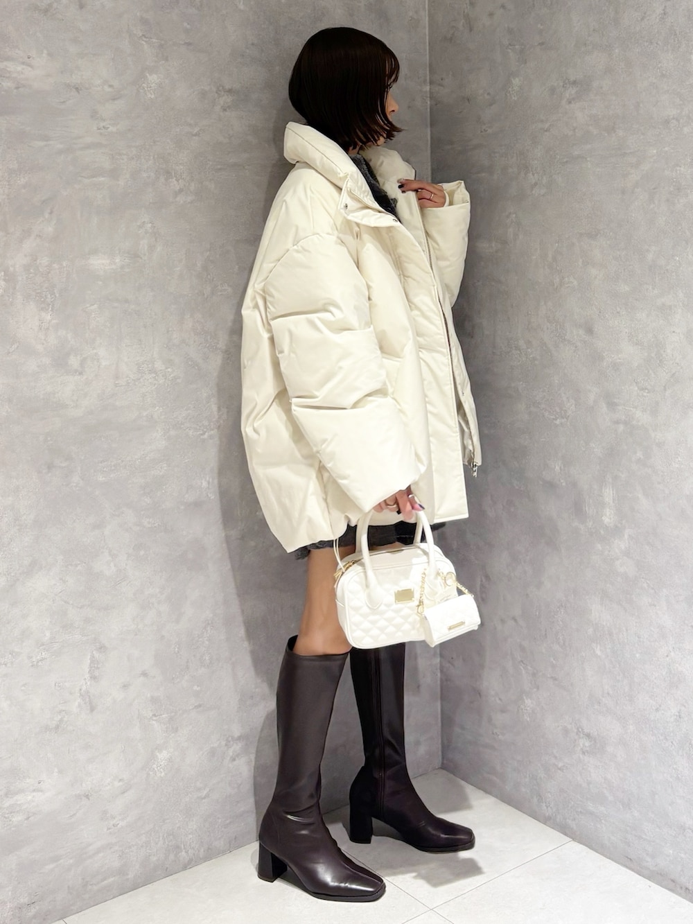 グレー系のワンピース、ホワイト系のダウンジャケット/コート、ホワイト系のハンドバッグを着用したレディースの冬コーディネートの2枚目の写真