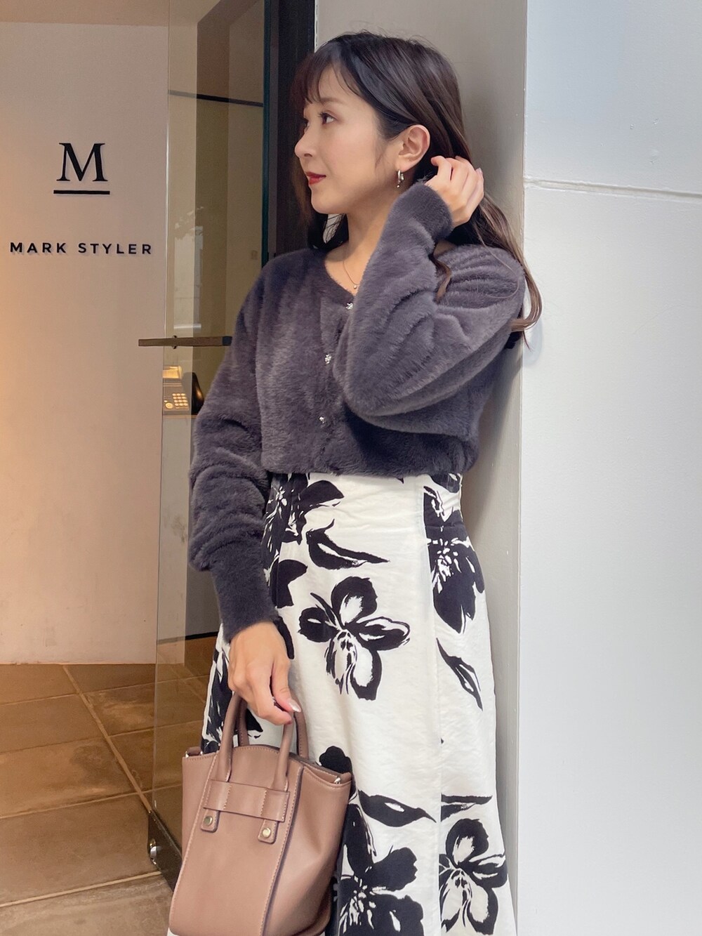 ブラウン系のハンドバッグ、ブラック系のブーツ、ホワイト系のスカートを着用したレディースの秋コーディネートの2枚目の写真