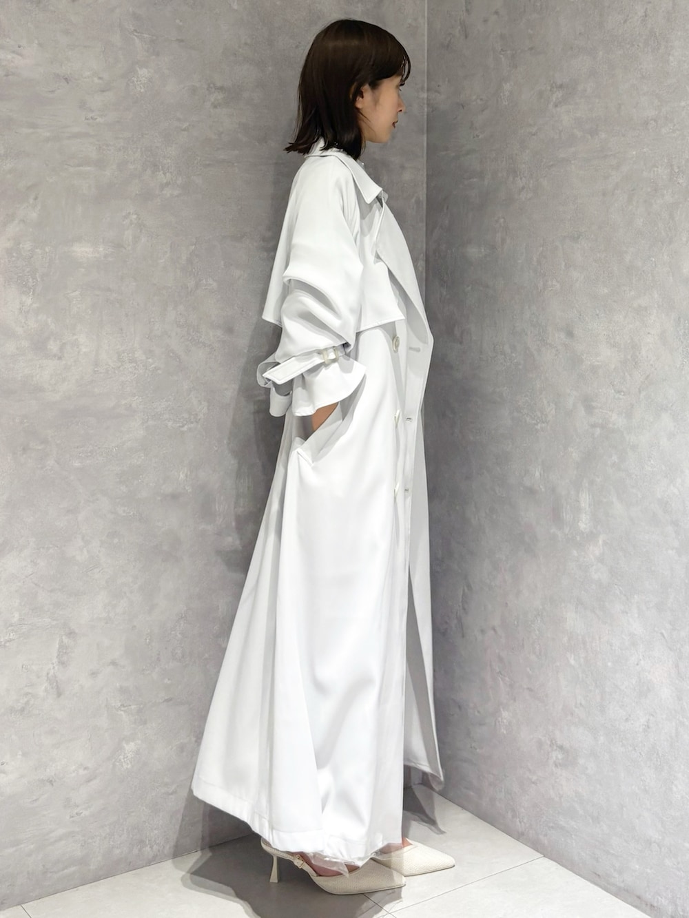 ホワイト系のスカート、ブルー系のトレンチコート、グリーン系のニット/セーターを着用したレディースの春コーディネートの3枚目の写真