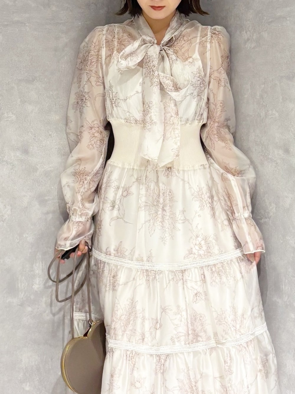 ベージュ系のショルダーバッグ、ホワイト系のブーツ、ベージュ系のワンピースを着用したレディースの冬コーディネートの6枚目の写真