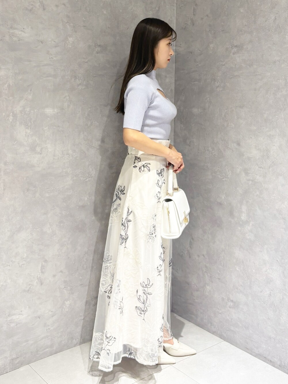 ベージュ系のスカート、ホワイト系のパンプス、ホワイト系のハンドバッグを着用したレディースの春コーディネートの2枚目の写真