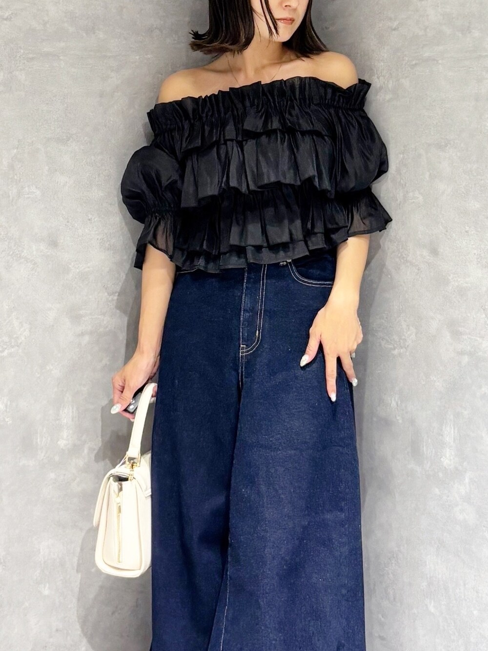 ブルー系のデニムパンツ、ブラウン系のサンダル、ホワイト系のハンドバッグを着用したレディースの夏コーディネートの6枚目の写真