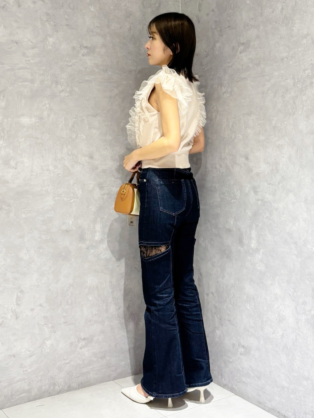 ブルー系のデニムパンツ、ピンク系のニット/セーター、ホワイト系のパンプスを着用したレディースの春コーディネートの5枚目の写真