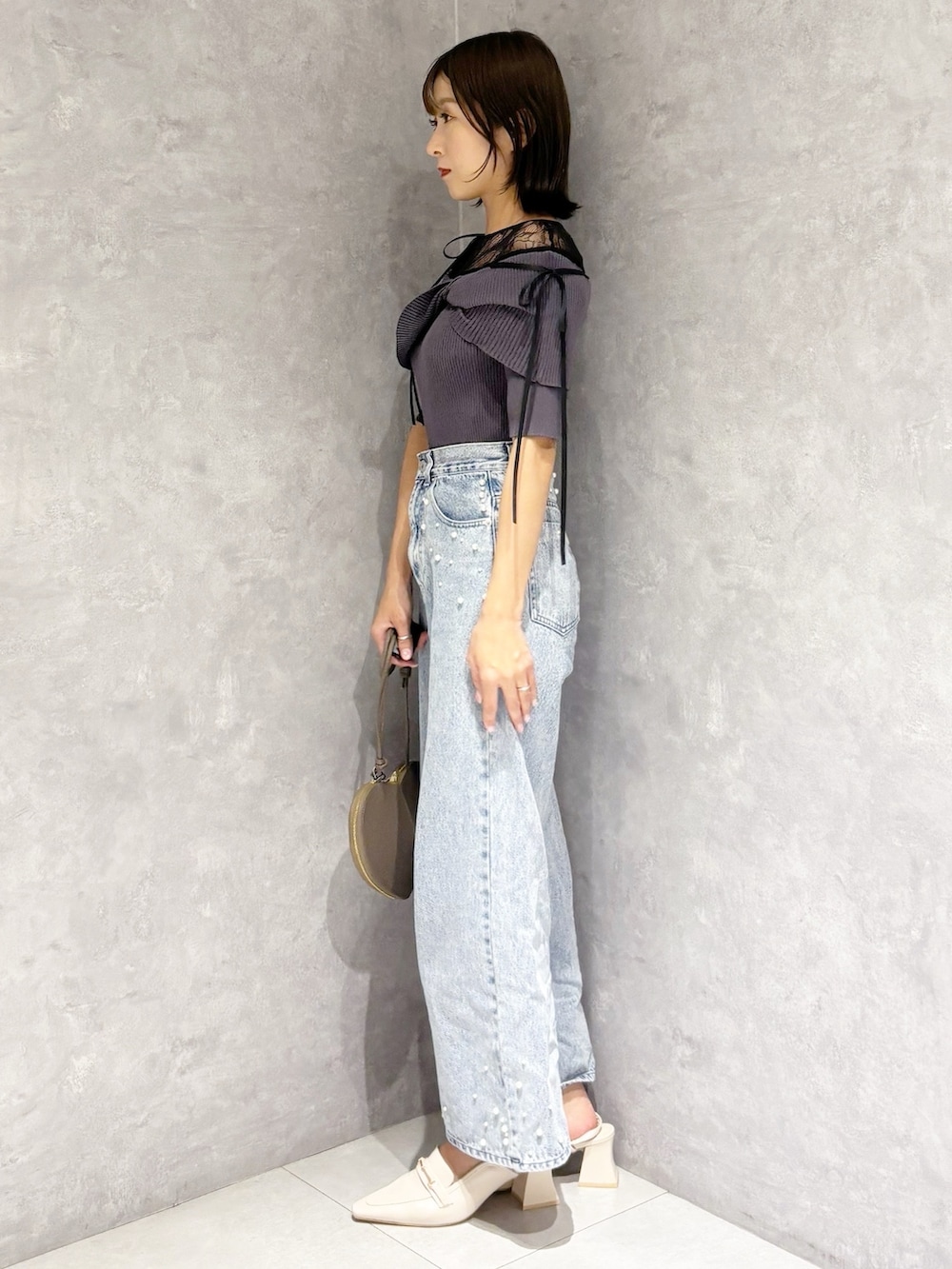 ブルー系のデニムパンツ、ホワイト系のパンプス、グレー系のニット/セーターを着用したレディースの春コーディネートの4枚目の写真