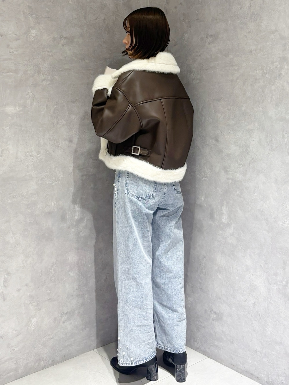 ブルー系のデニムパンツ、ベージュ系のニット/セーター、ブラック系のブーツを着用したレディースの冬コーディネートの3枚目の写真