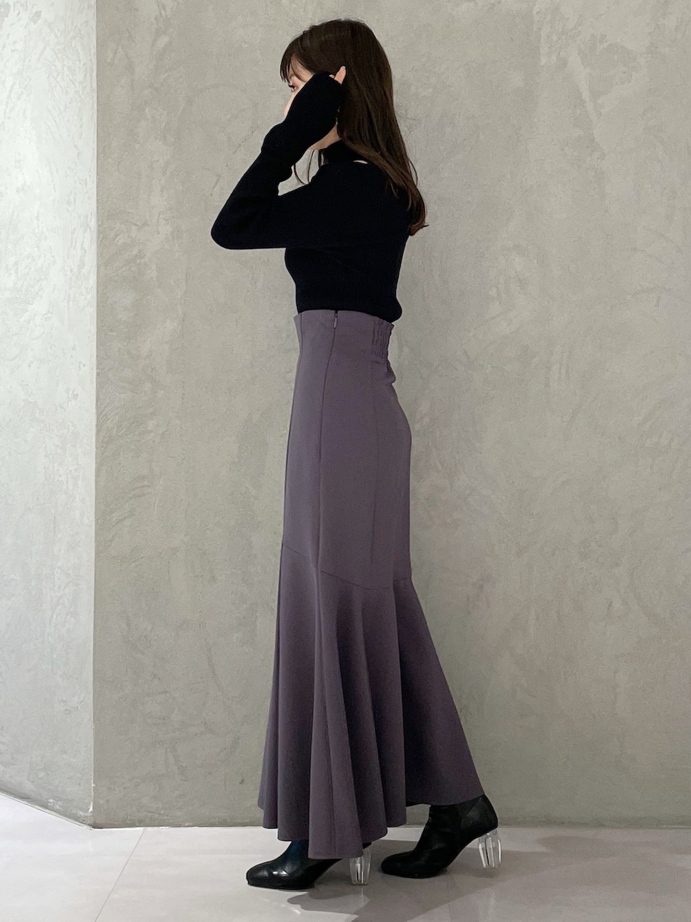 グレー系のスカート、グレー系のニット/セーター、ブラック系のブーツを着用したレディースの冬コーディネートの2枚目の写真